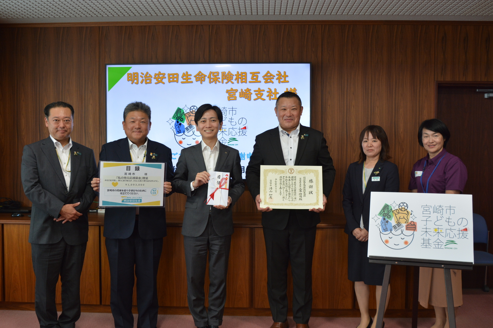 市長と子ども未来部長と明治安田生命保険相互会社宮崎支社様の集合写真