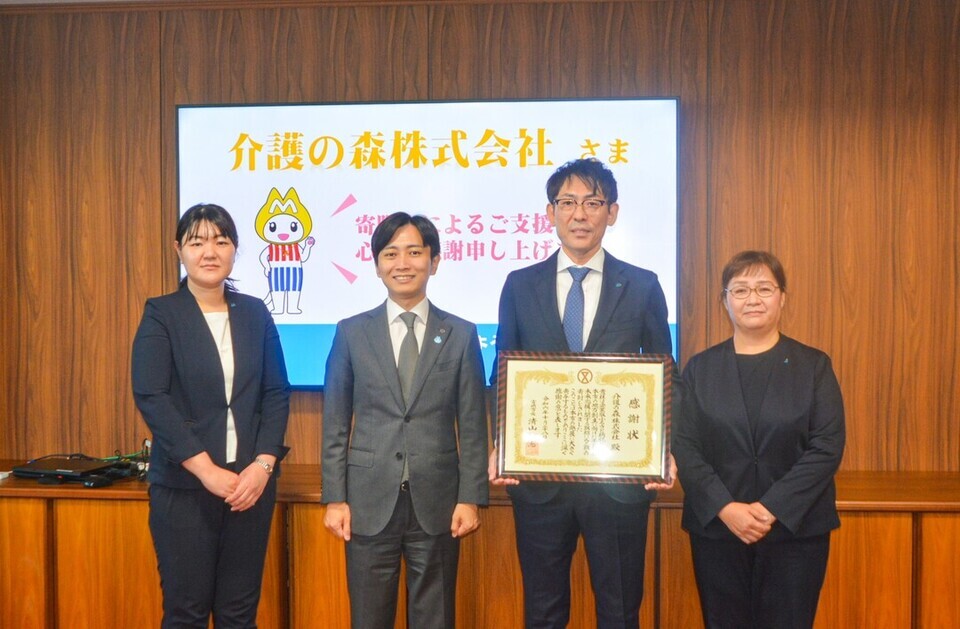 感謝状を手に持つ4人の集合写真