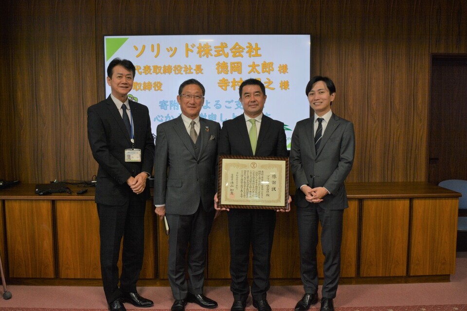 感謝状を手に持つ4人の集合写真